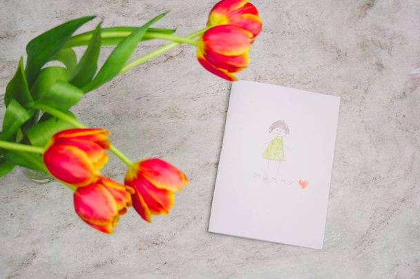 hermosos tulipanes y tarjeta hecha a mano con dibujo de niño para el Día de la Madre sobre fondo de mármol, vista superior
 - Foto, imagen