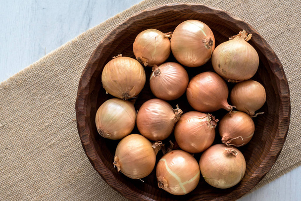 Raw organic onions on rustic wooden bowl. Table background. - Photo, Image