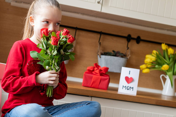 Cute young girl holding bouquet of red roses for her mom. Family celebration concept. Happy Mother's Day or Birthday Background.  - Fotoğraf, Görsel