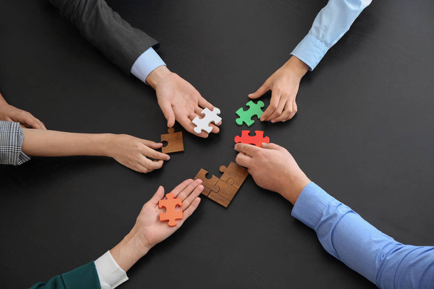 Business team samenstellen van puzzel op donkere tafel - Foto, afbeelding