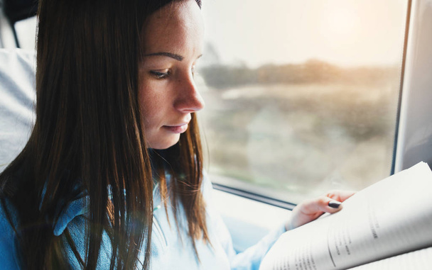 Student girl reading literature train - Foto, Imagen