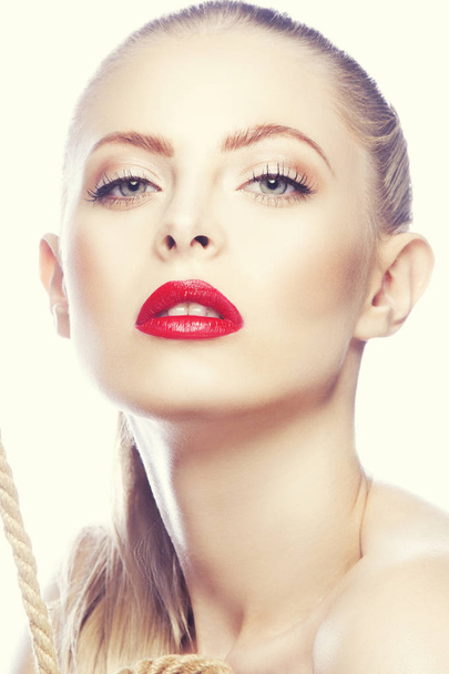 Portrait of woman with modern red lips makeup and rope in hands - Фото, изображение