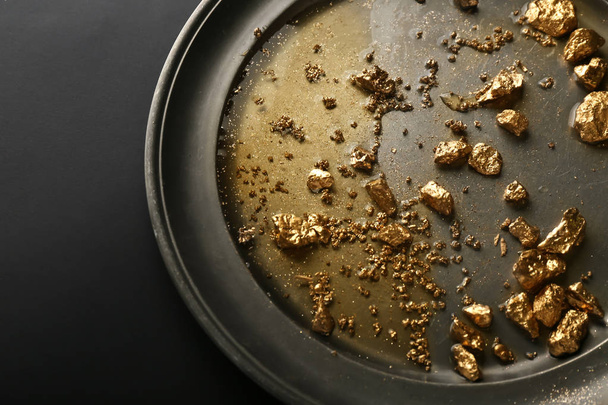 Plate with gold nuggets on black background - Photo, Image