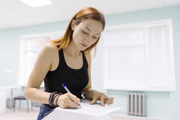 Young beautiful woman signing business papers indoors. - Φωτογραφία, εικόνα