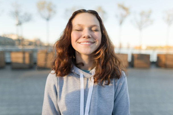 Portrait of a happy teen girl with eyes closed, golden hour. - Photo, image