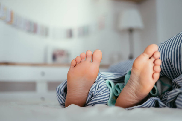 Naked feet of a young girl in bed, morning - 写真・画像