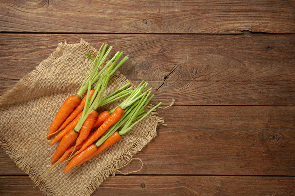 Fresh baby carrots on wooden cutting board and wooden background. - Photo, Image