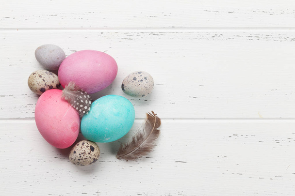 Easter greeting card with colorful eggs and little quail eggs on wooden white background - Fotó, kép