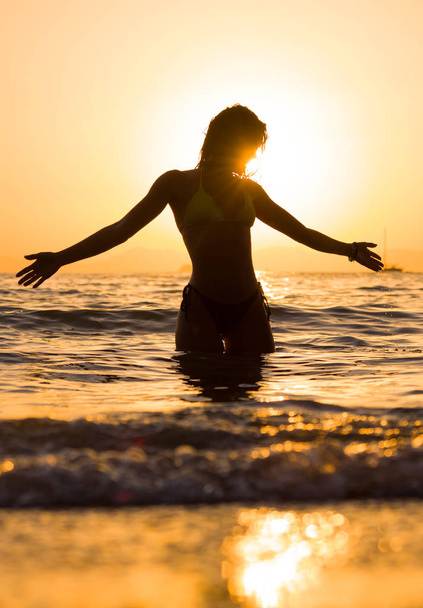 young woman walking in the sea at sunset - Фото, зображення