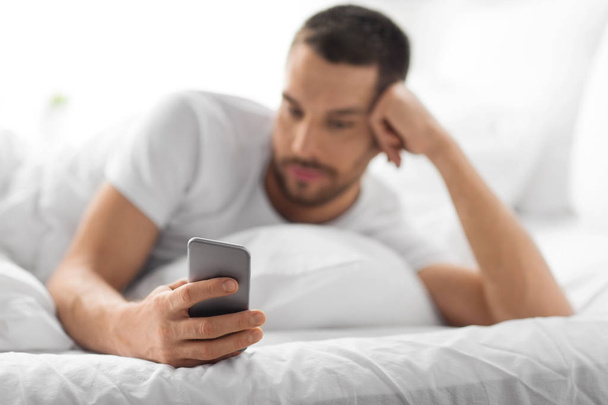 close up of man with smartphone in bed in morning - Фото, зображення