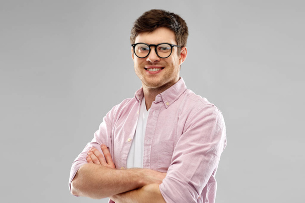 smiling young man in glasses over grey background - Foto, Bild