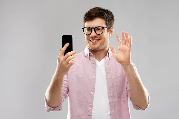 smiling man having video call on smartphone - Foto, afbeelding