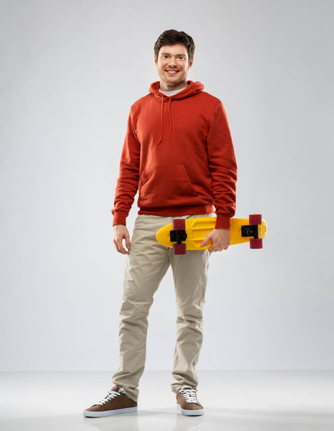 smiling young man in hoodie with short skateboard - Foto, Imagem