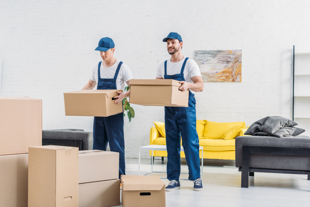 two movers transporting cardboard boxes in apartment - Photo, Image