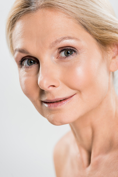 close up of beautiful and blonde mature woman looking at camera isolated on grey  - 写真・画像