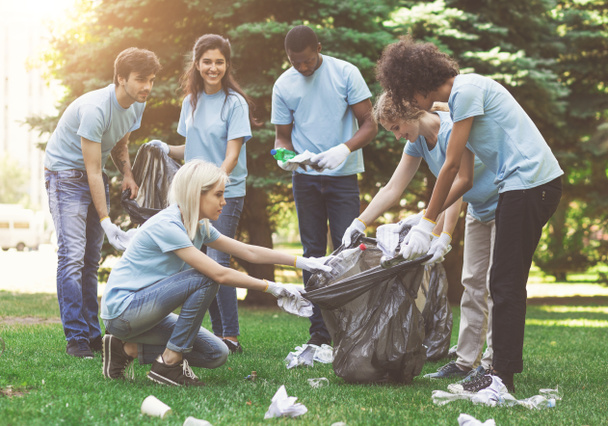 Young volunteers collecting garbage in suumer park - Photo, Image
