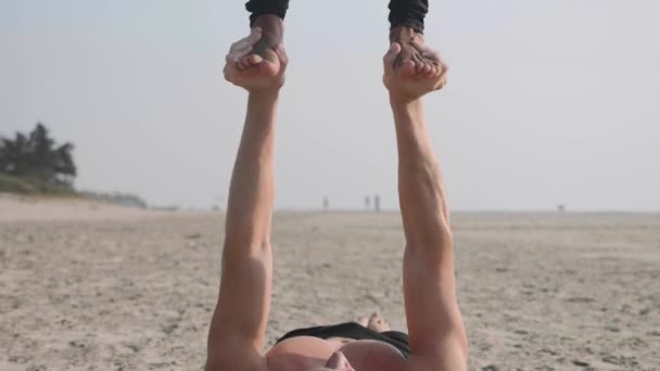 Dopasowanie sportowy para praktykowania jogi acro z partnerem razem na plaży. - Materiał filmowy, wideo