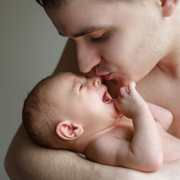 Père tient son fils nouveau-né entre ses mains. Le garçon pleure, l'homme essaie de le calmer. La vie familiale. L'homme est né
. - Photo, image