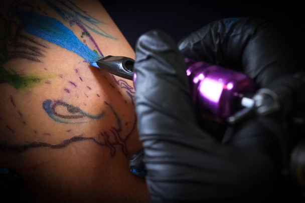 Vrouwelijke tatoeëerder maken van tatoeage op arm een mannen - Foto, afbeelding