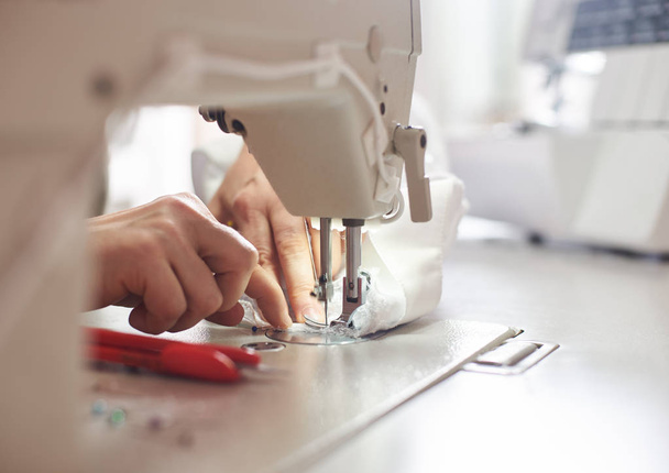 zblízka ženské ruce šití bílé tkaniny na profesionální výrobu stroje na pracovišti - Fotografie, Obrázek
