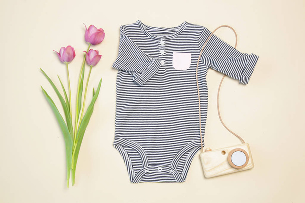 Baby lente outfit, bovenaanzicht, ontdaan lichaam, houten camera speelgoed en roze tulpen - Foto, afbeelding