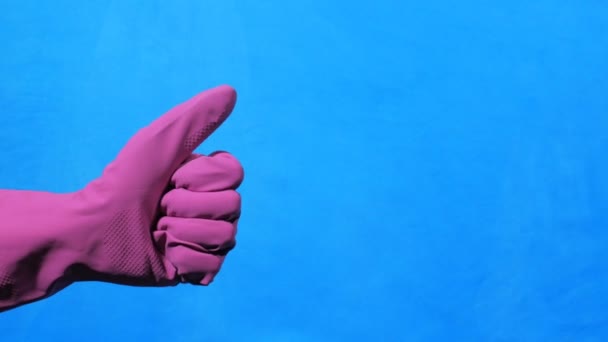 Cleaner hand in purple rubber glove on blue background. Like gesture. - Πλάνα, βίντεο