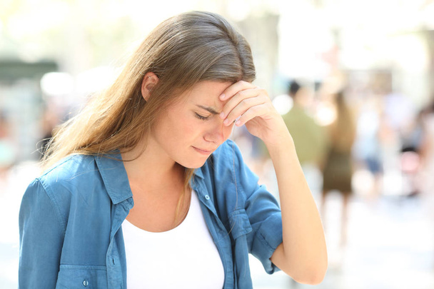 Girl suffering headache standing in the street - Фото, изображение