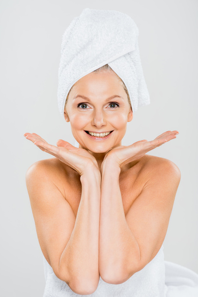 attractive and smiling mature woman in towels looking at camera isolated on grey - Foto, immagini