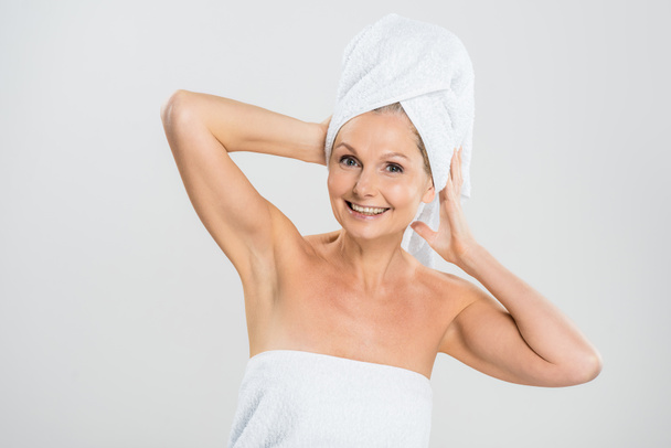 attractive and smiling mature woman in towels looking at camera isolated on grey - Foto, Bild