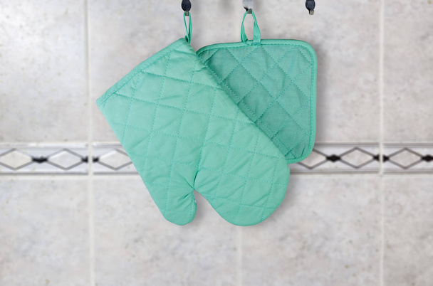 Hanging oven glove and pot-holder against wall with tile - Photo, Image