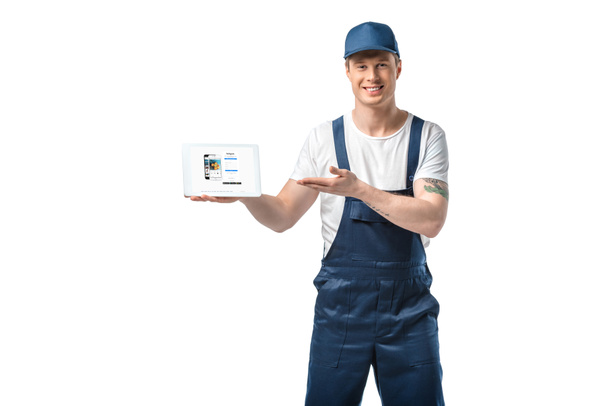 handsome smiling mover gesturing with hand while presenting digital tablet with instagram app on screen isolated on white - Φωτογραφία, εικόνα