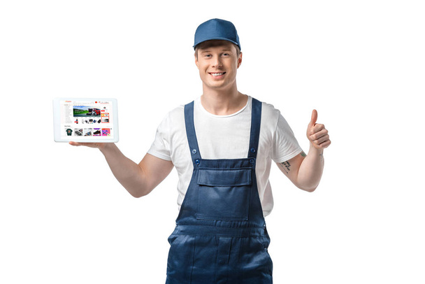 handsome smiling mover showing thumb up and presenting digital tablet with aliexpress app on screen isolated on white - Foto, immagini