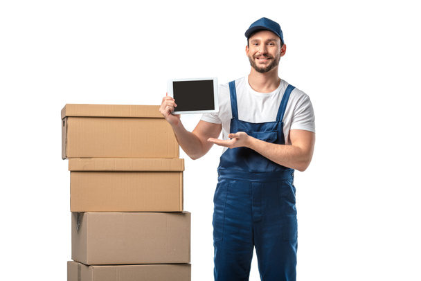  mover with cardboard boxes looking at camera and presenting digital tablet with blank screen isolated on white - Φωτογραφία, εικόνα