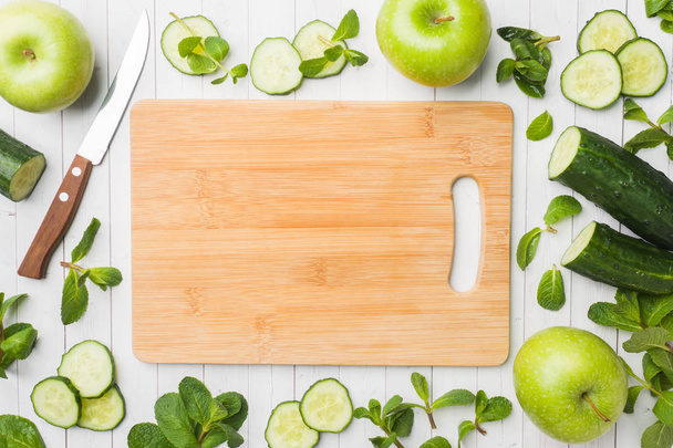 Green cucumber mint Apple on the table. The concept of diet and vegetarianism. Copy space. Empty wooden cutting Board. - Photo, image