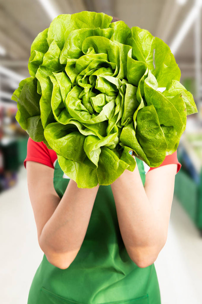 Woman at grocery store hiding behind lettuc - Photo, Image