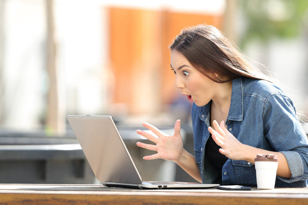 Amazed woman finding online content on laptop in a park - Φωτογραφία, εικόνα