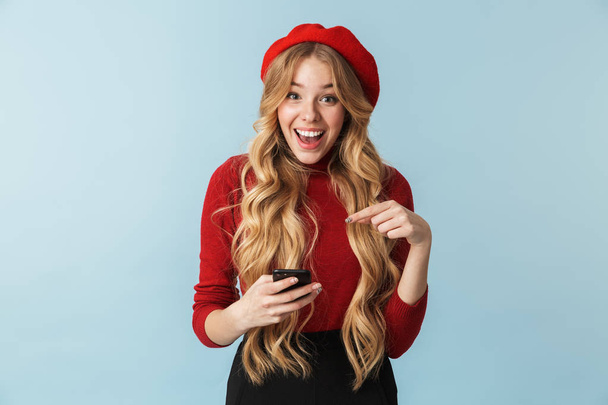 20-as a vonzó lány visel piros beret használ smartphone-fotó - Fotó, kép