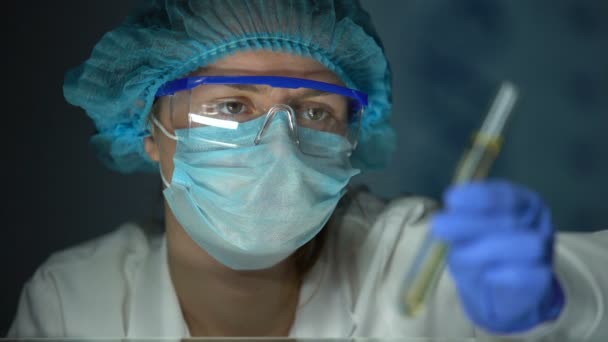 Lab assistant looking at tube with transparent yellow liquid, biofuel testing - Filmagem, Vídeo