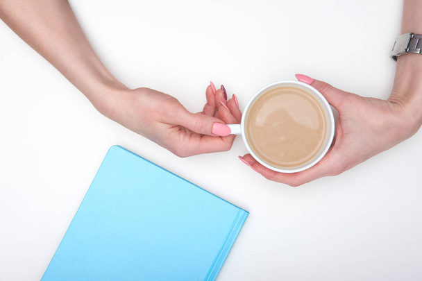 Hands of woman, holding cup of latte and blue covered diery on w - Photo, Image