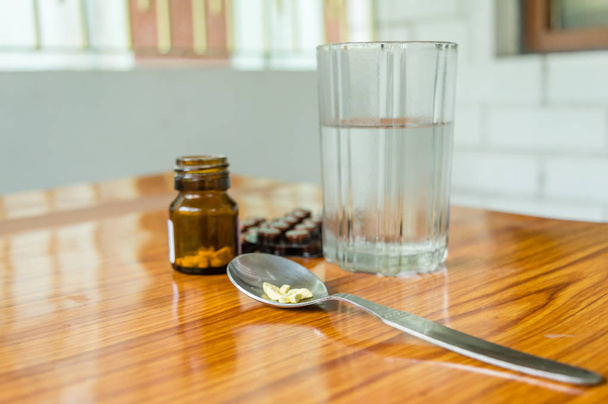Tekintse meg az antioxidánsok vitamin tabletta, tabletta buborékcsomagolás, egy üveg gyógyszer, kapszula mérőkanál, egy pohár vízzel az asztalra. Orvosi patika téma. Oldalnézet, közeli fénymásolás. - Fotó, kép