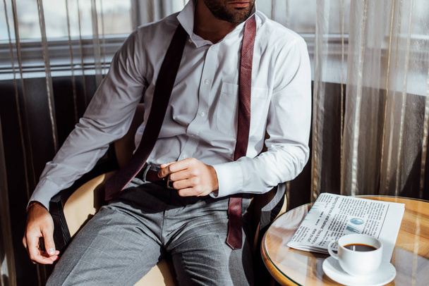 kahve masanın fincan kahve ve gazete ile takım elbiseli adam görünümünü kırpılmış  - Fotoğraf, Görsel