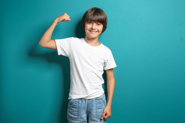 Petit garçon en t-shirt montrant les muscles sur fond de couleur
 - Photo, image