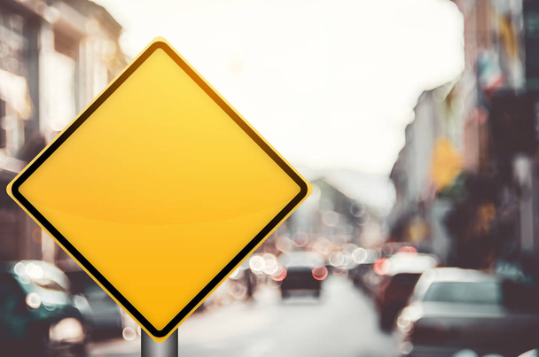 leeres gelbes Verkehrszeichen auf verschwommener Verkehrsstraße mit buntem Bokeh-Licht abstrakter Hintergrund. - Foto, Bild