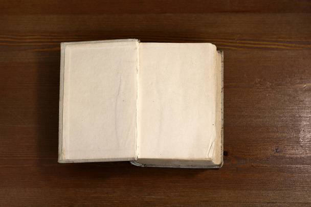 Otwartej książki stare retro biały puste puste strony, na których projektant można napisać tekst powitania lub pocztówkę na drewnianym tle atmosfery biblioteki - Zdjęcie, obraz
