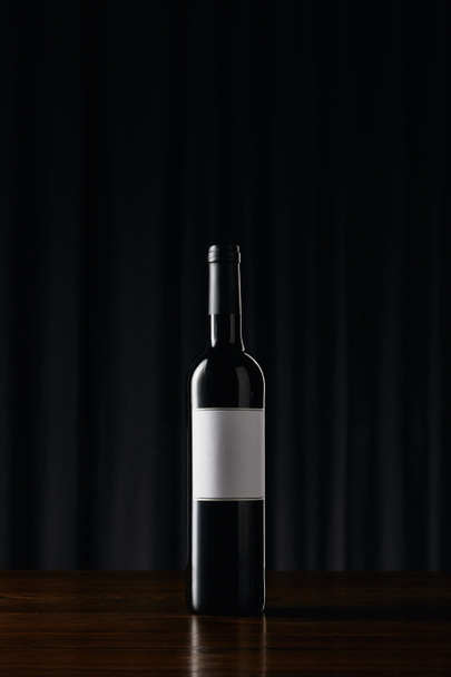 WIne bottle with blank label on wooden surface - Valokuva, kuva