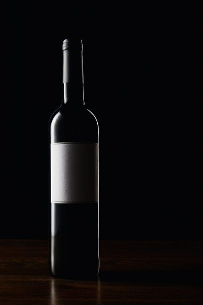 Wine bottle with blank label on wooden surface - 写真・画像