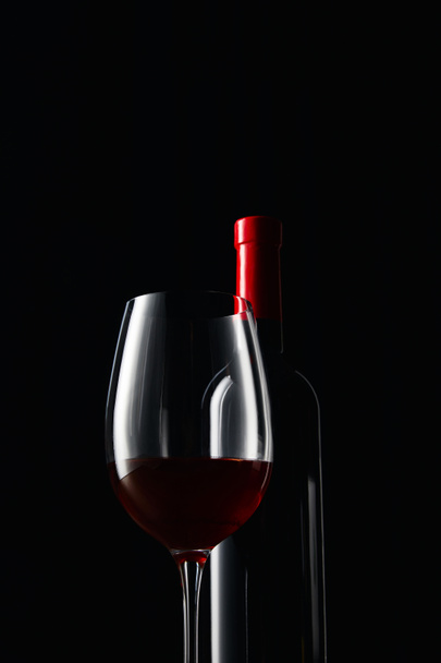 Bottle and glass of red wine isolated on black - Foto, Imagem