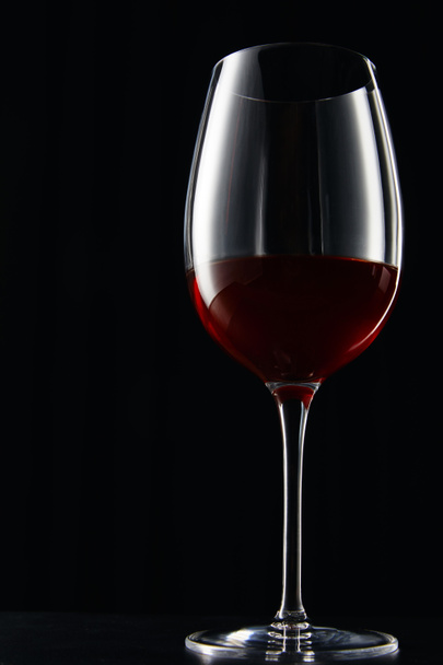 Glass of red wine on dark surface isolated on black - Фото, зображення
