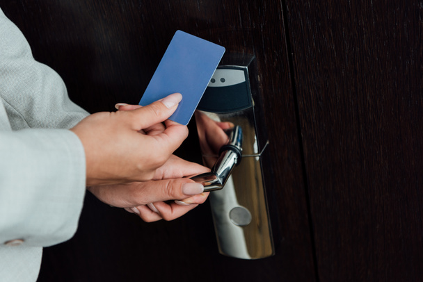 cropped view of woman holding hotel card while opening hotel door  - Fotografie, Obrázek