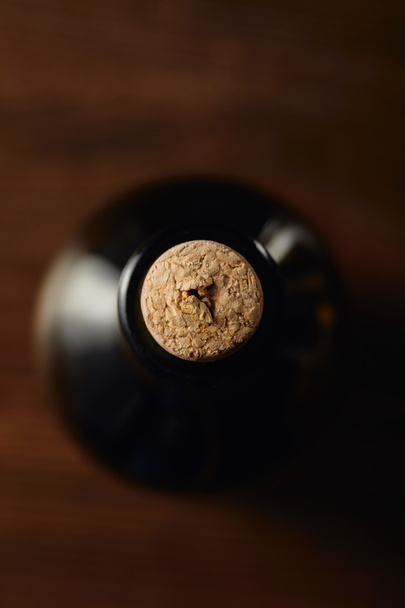 Top view of wine bottle with wooden cork on brown surface - Foto, imagen